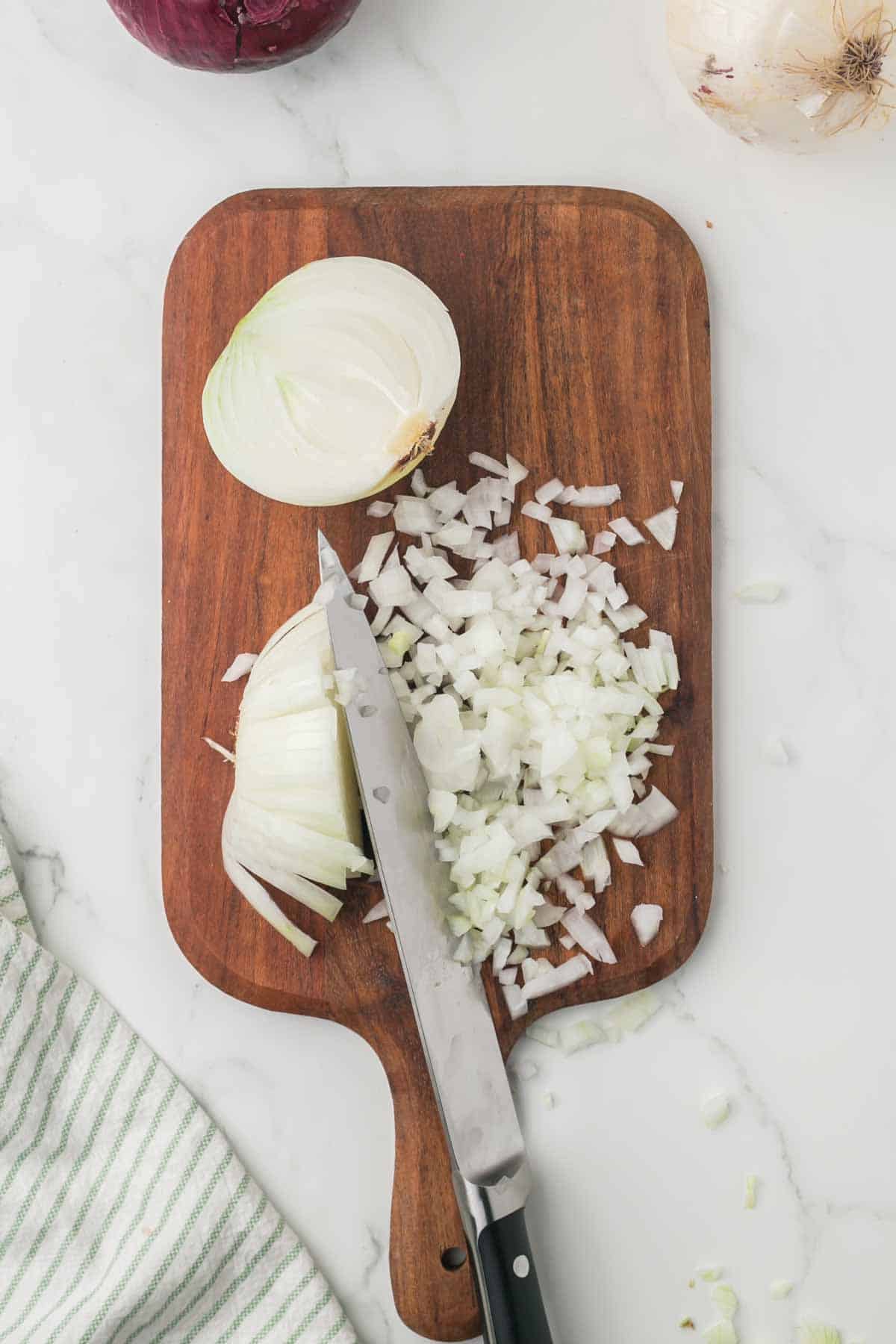 how to dice an onion, white onion on a wooden chopping block step by step