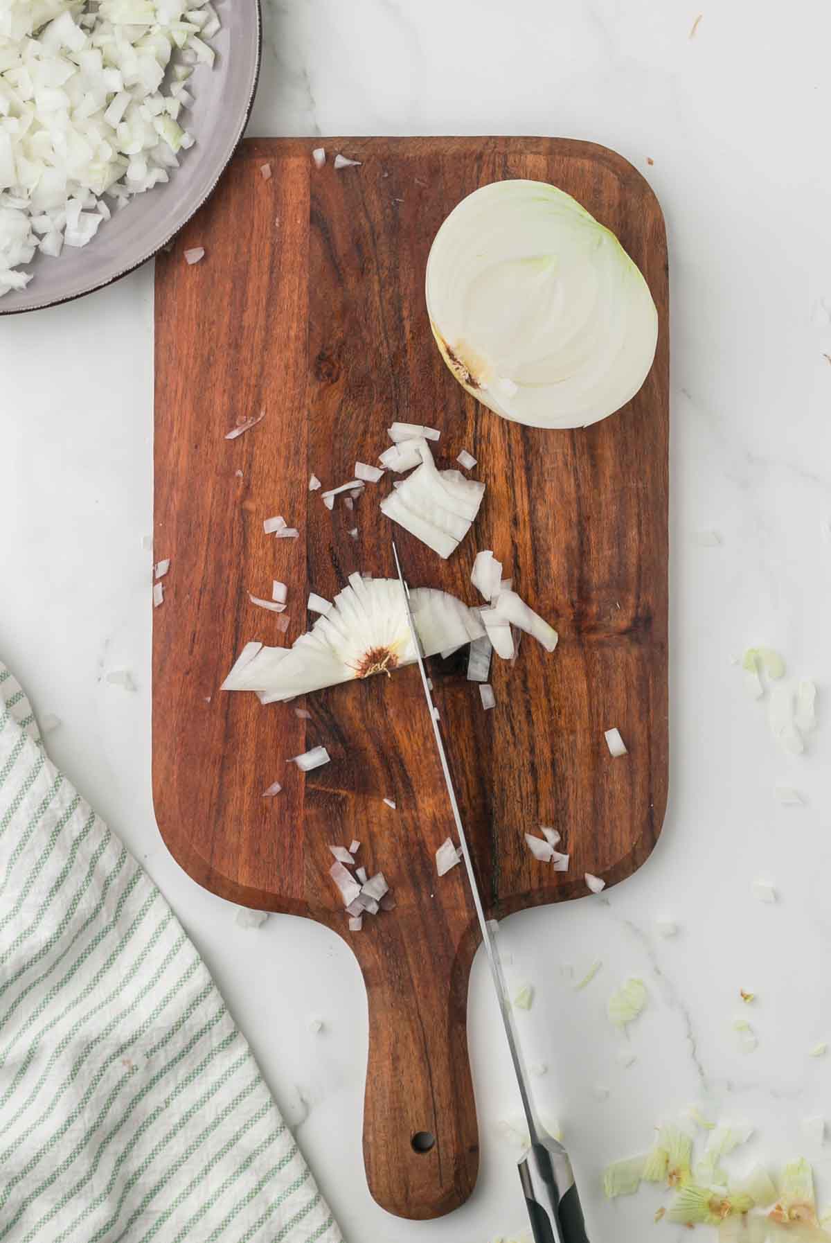 how to dice an onion, white onion on a wooden chopping block step by step