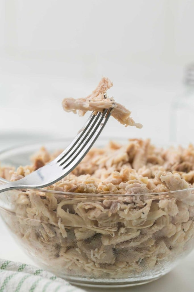 shredded chicken in a clear bowl and a fork dipped into it