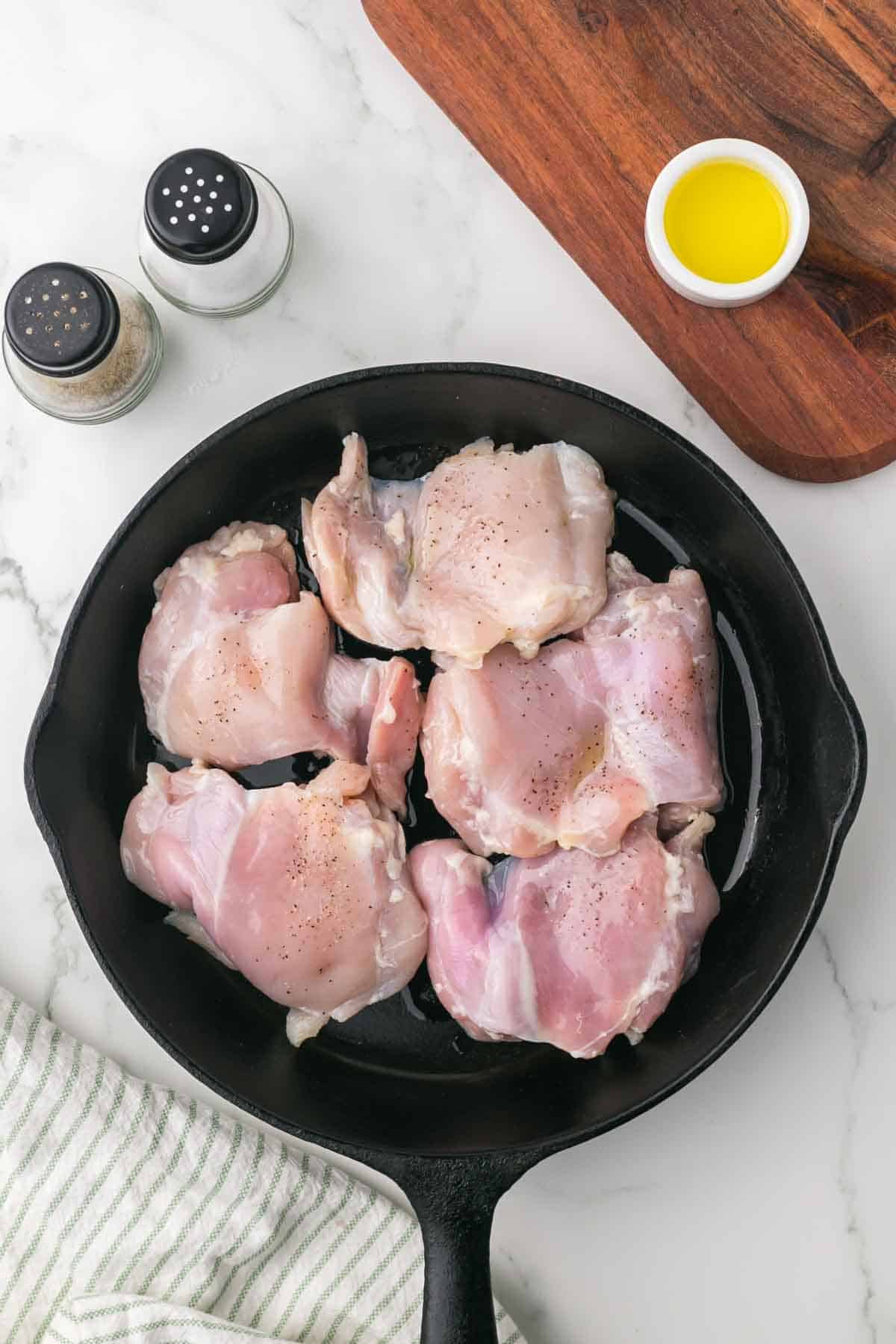 raw chicken and oil in a cast iron pan