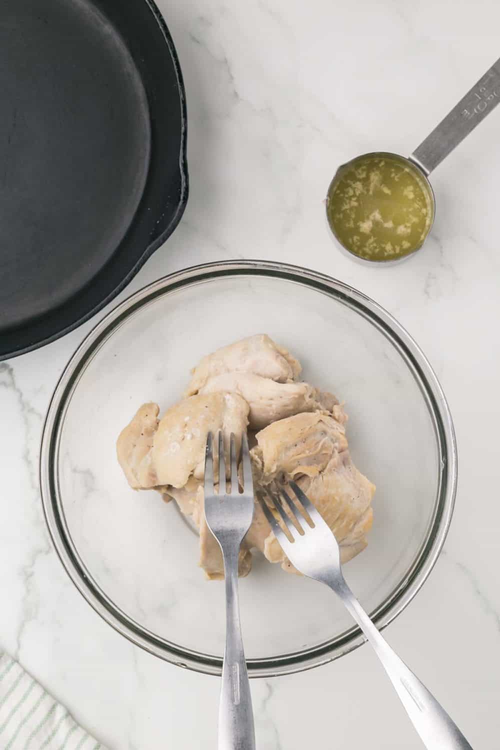 cooked chicken in a bowl with forks ready to shred it