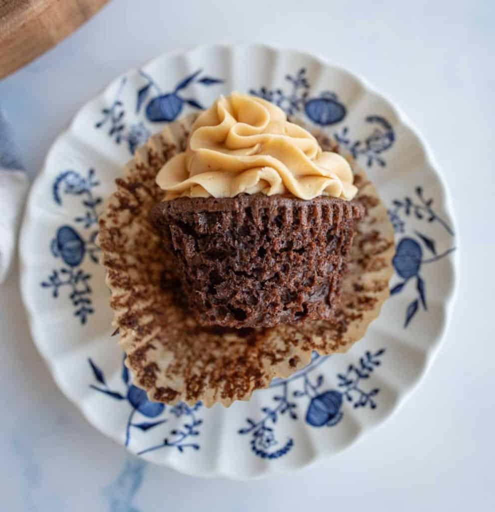 side view of the wrapper opened up on a chocolate cupcake with peanut butter frosting on a china plate