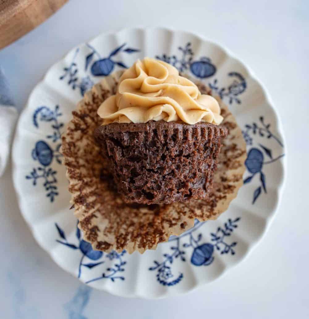 side view of the wrapper opened up on a chocolate cupcake with peanut butter frosting on a china plate