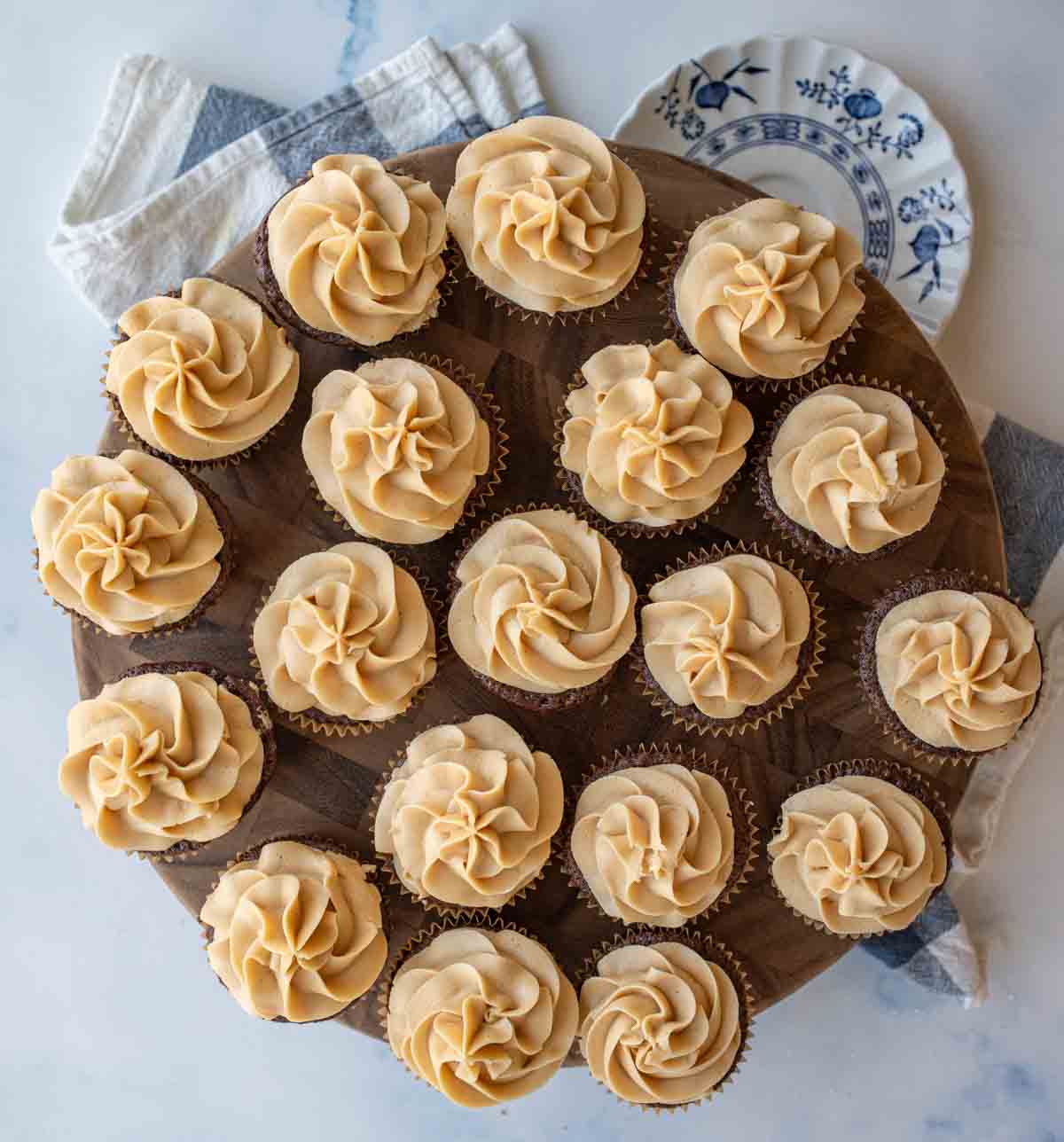 aesthetic top view photo of fluffy peanut butter frosting piped onto a round board of cupcakes