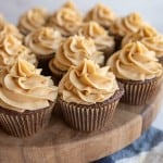 fluffy beige frosting pipped onto a plate of chocolate cupcakes