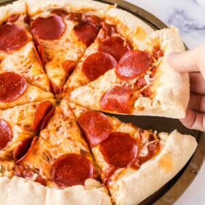 POV hand scooping a slice of stuffed crust pizza