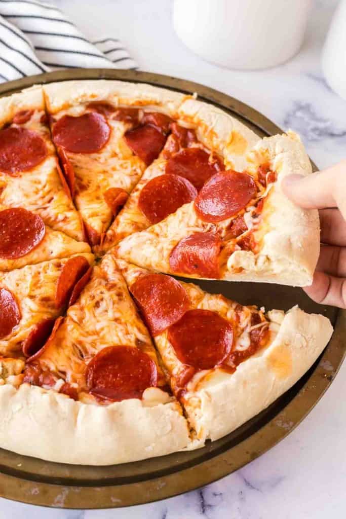 POV hand scooping a slice of stuffed crust pizza