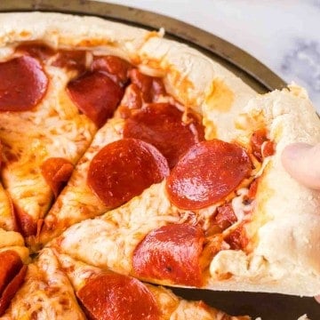 POV hand scooping a slice of stuffed crust pizza