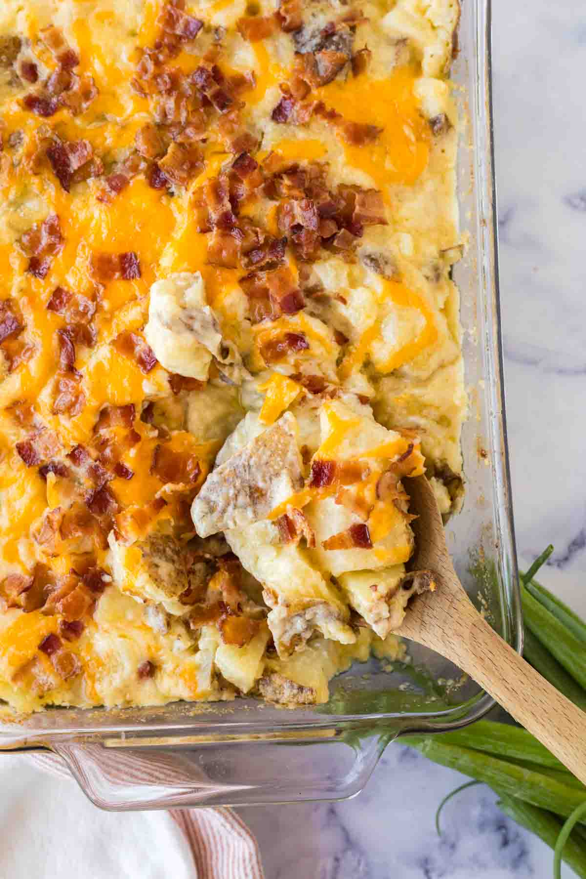 close up of twice baked casserole and a wooden spoon scooping it out