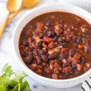 two white bowl with vegetarian chili and golden spoons