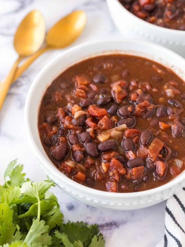 two white bowl with vegetarian chili and golden spoons