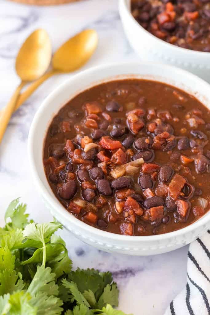two white bowl with vegetarian chili and golden spoons