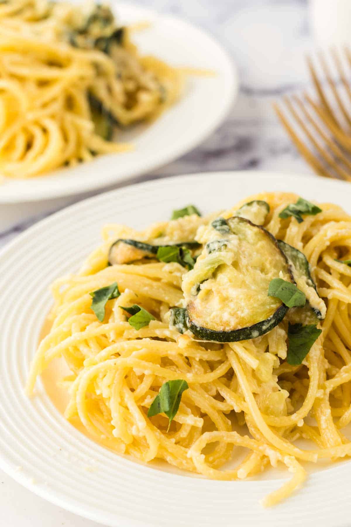 pasta with sliced zucchini and chives in a white dish