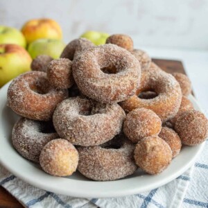 apple cider donuts and holes dusted with sugar on a white plate