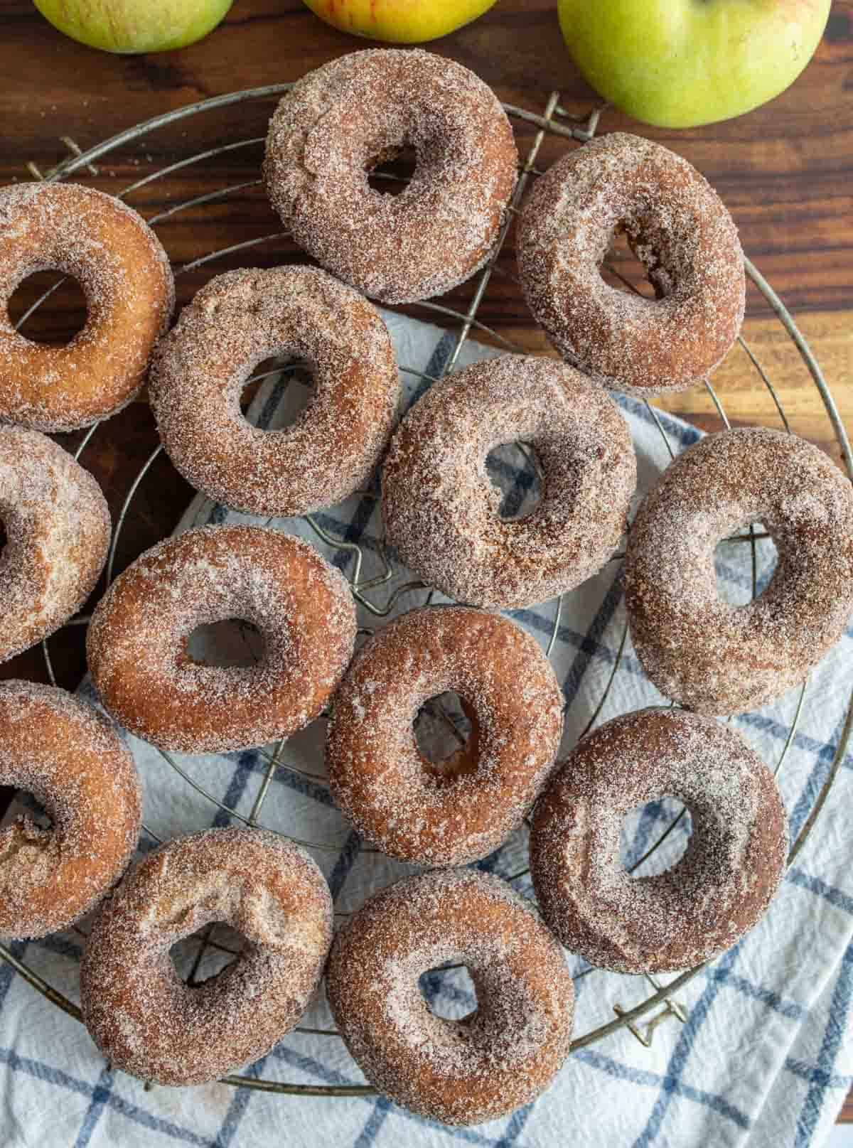 top view of apple cider donuts and holes dusted with sugar on a cooling rack