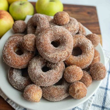 apple cider donuts and holes dusted with sugar on a white plate