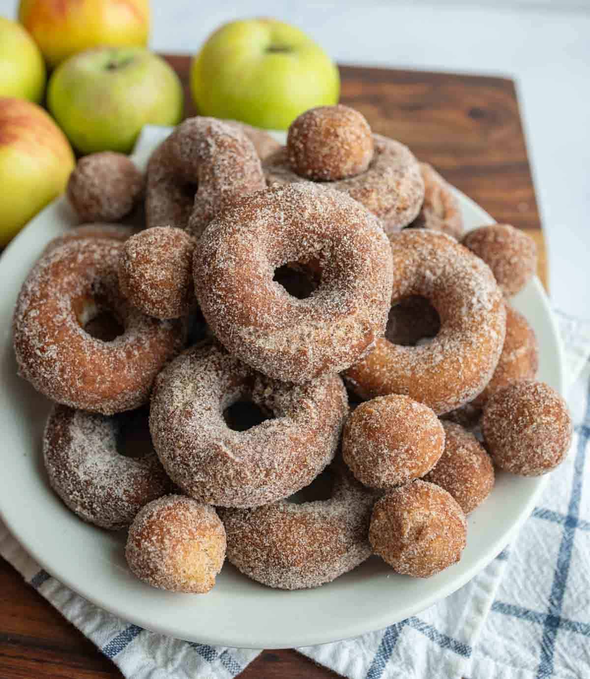 apple cider donuts and holes dusted with sugar on a white plate