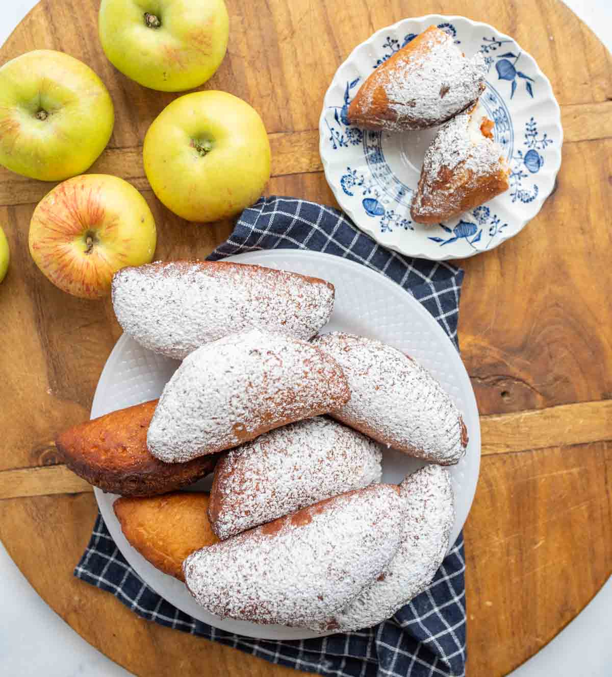 top view of apple hand pies dusted in sugar on neat plates with whole apples around