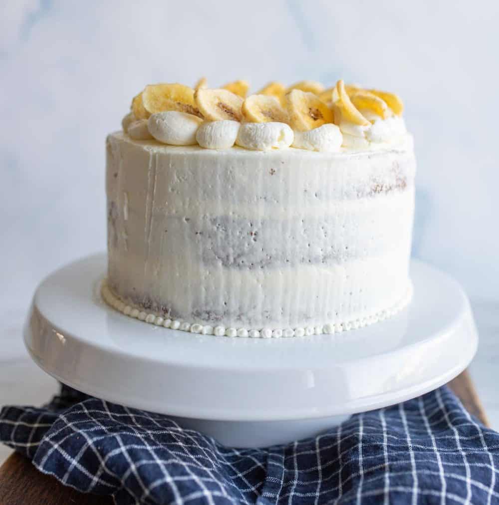 whole side view of three layer banana cake with white frosting