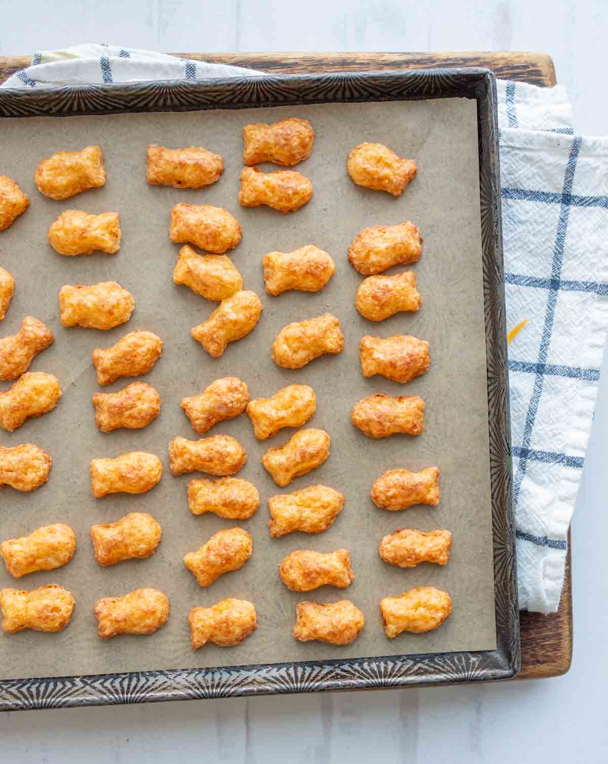 baked cheese crackers in a fish shape on a baking sheet