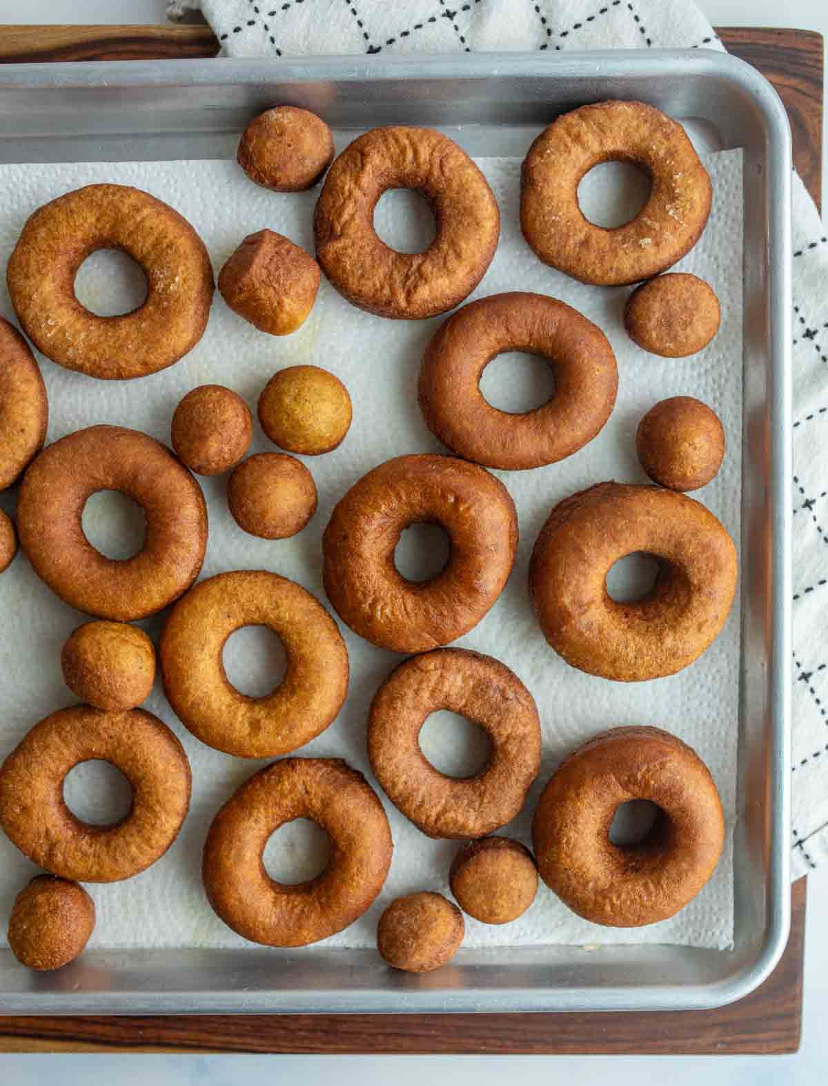 top view of a baking sheet with un coated pumpkin donuts
