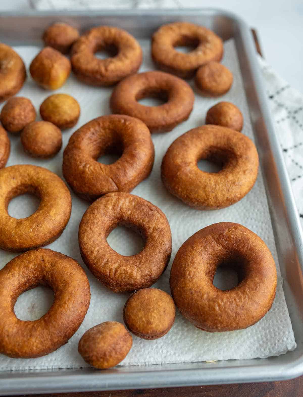 a baking sheet with un coated pumpkin donuts