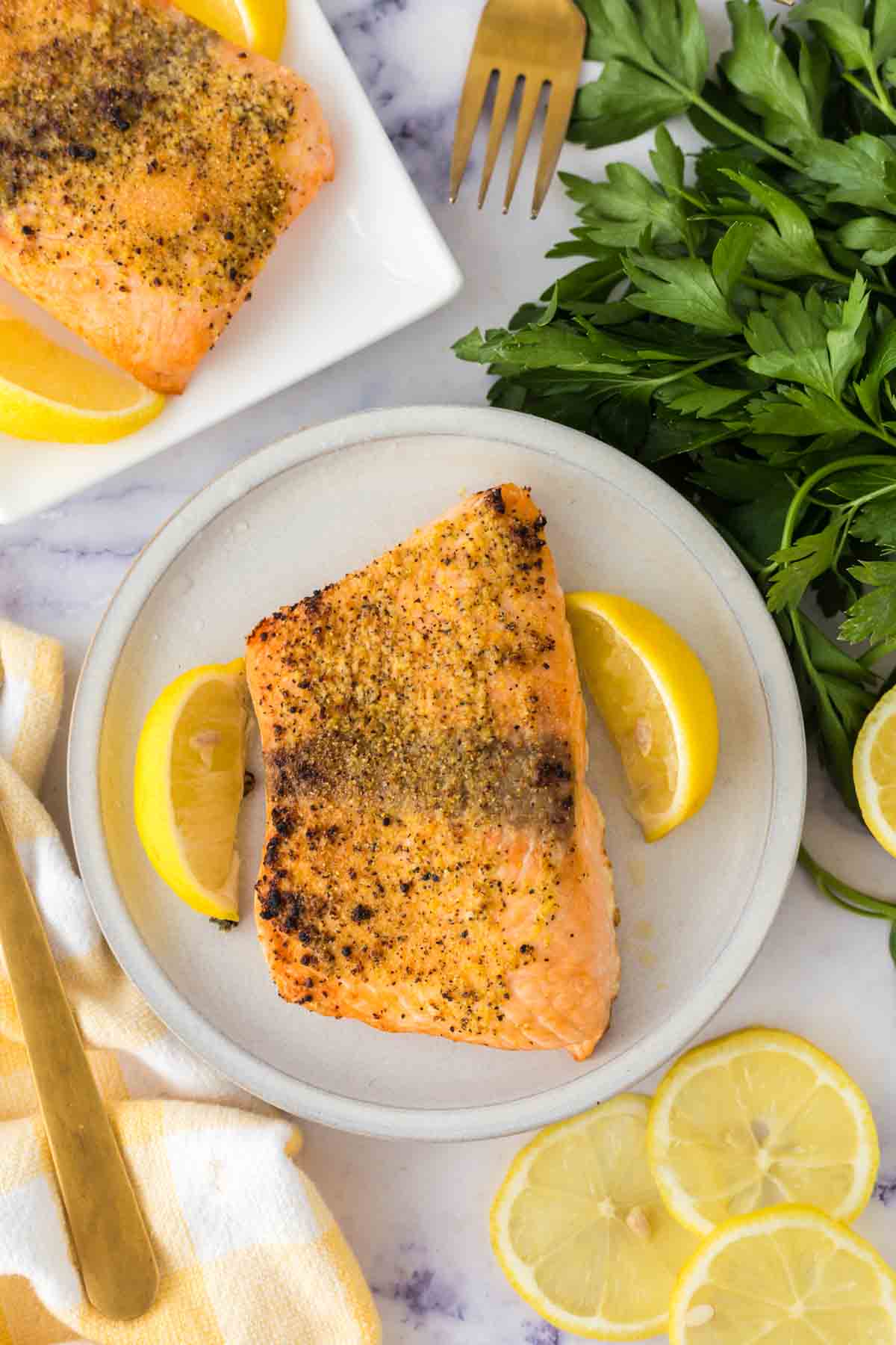 Single salmon filet on a plate served with lemons