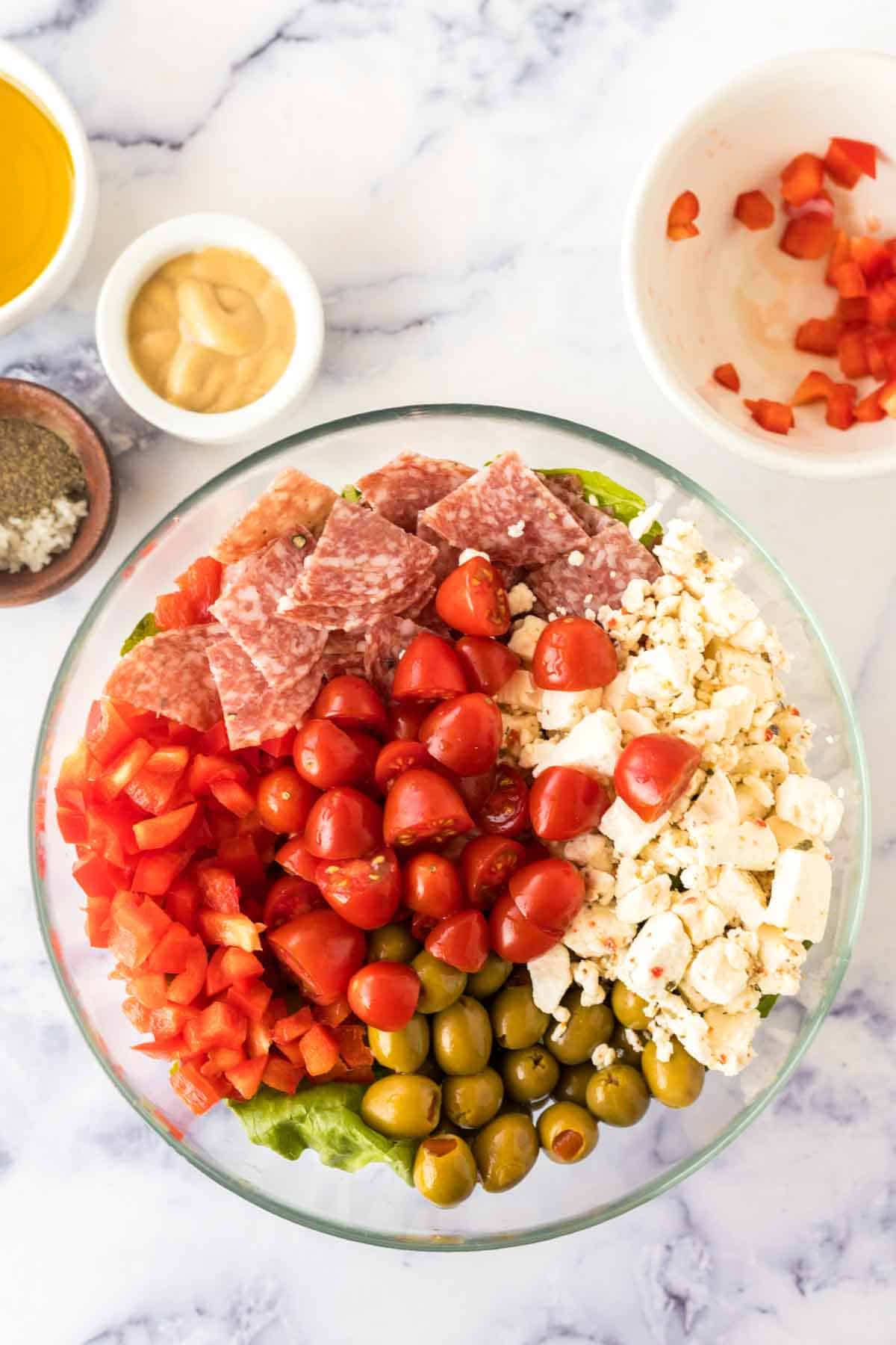Mixing ingredients together in a bowl to make antipasto salad.