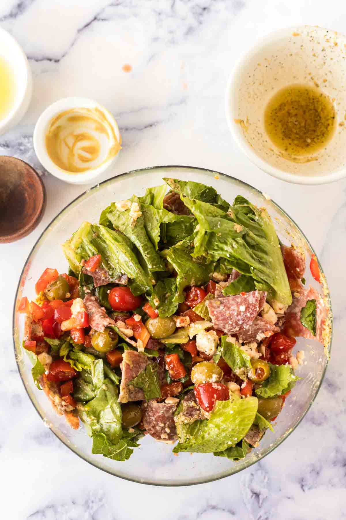 Pouring dressing over an almost complete antipasto salad.