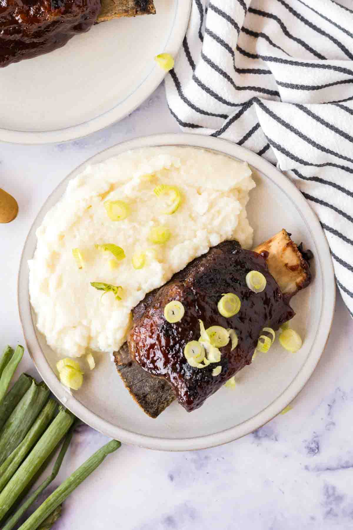 Beef short ribs served with potatoes on a plate. 