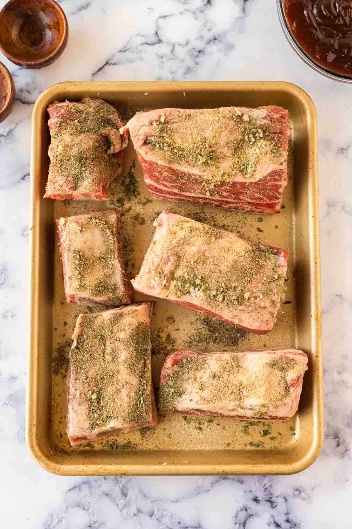Uncooked beef short ribs on a baking sheet.