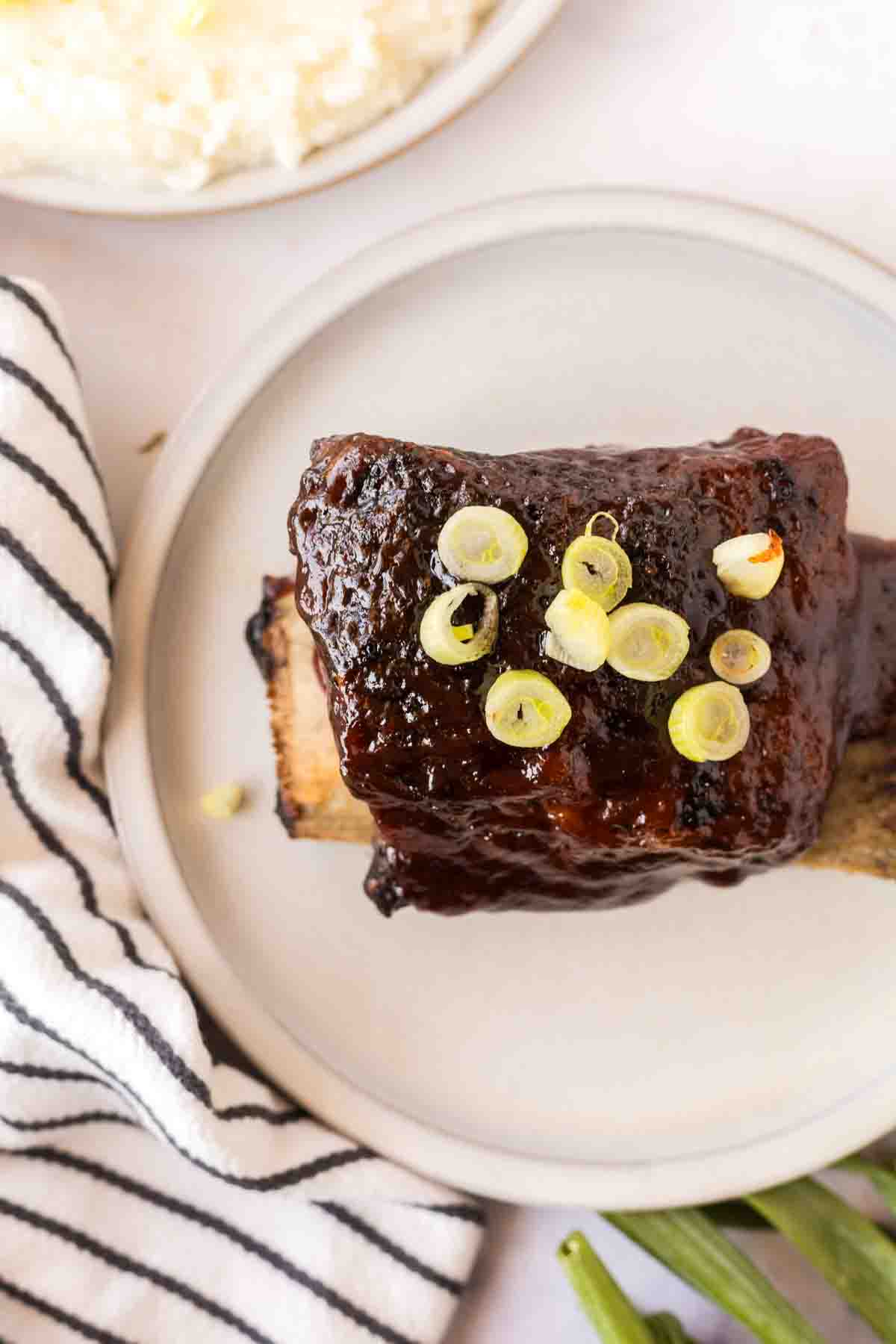 Top view of beef short ribs served on a white plate.