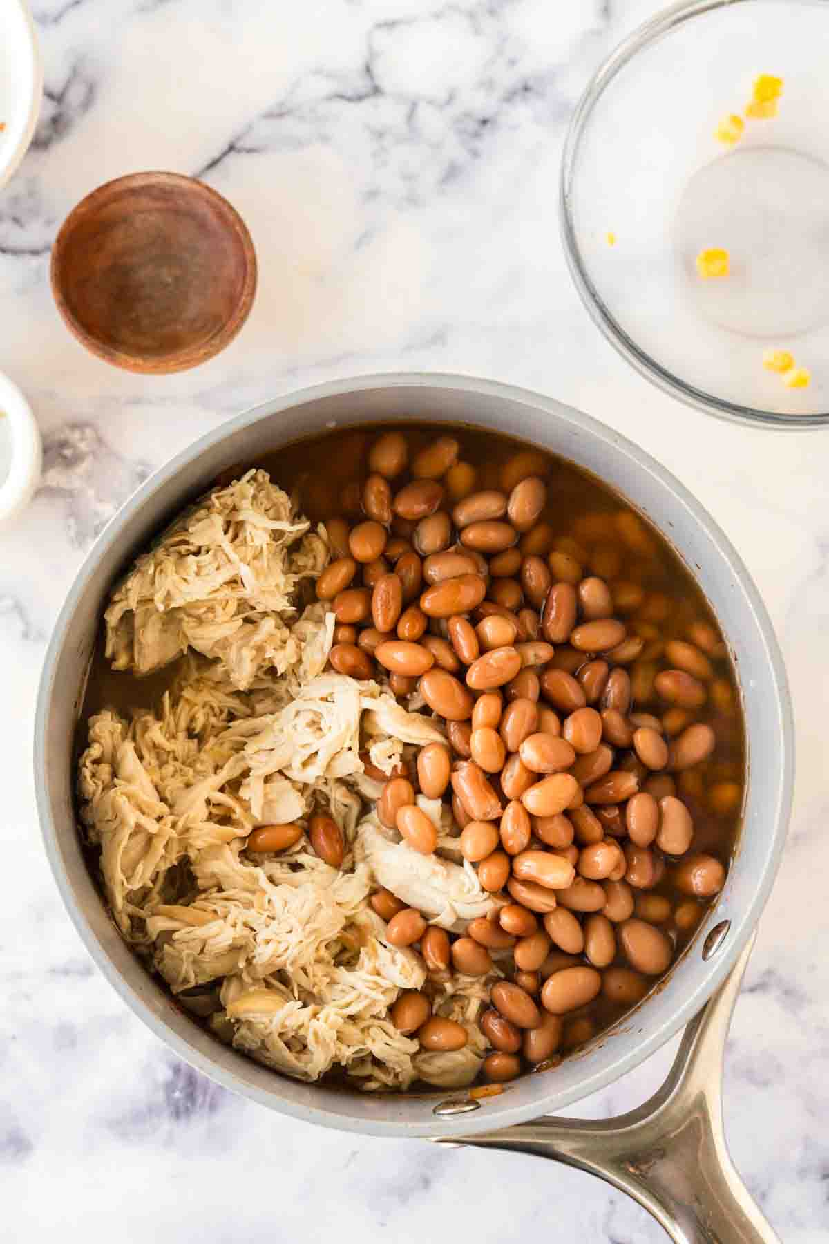 Chicken added to a large pot of brunswick stew.