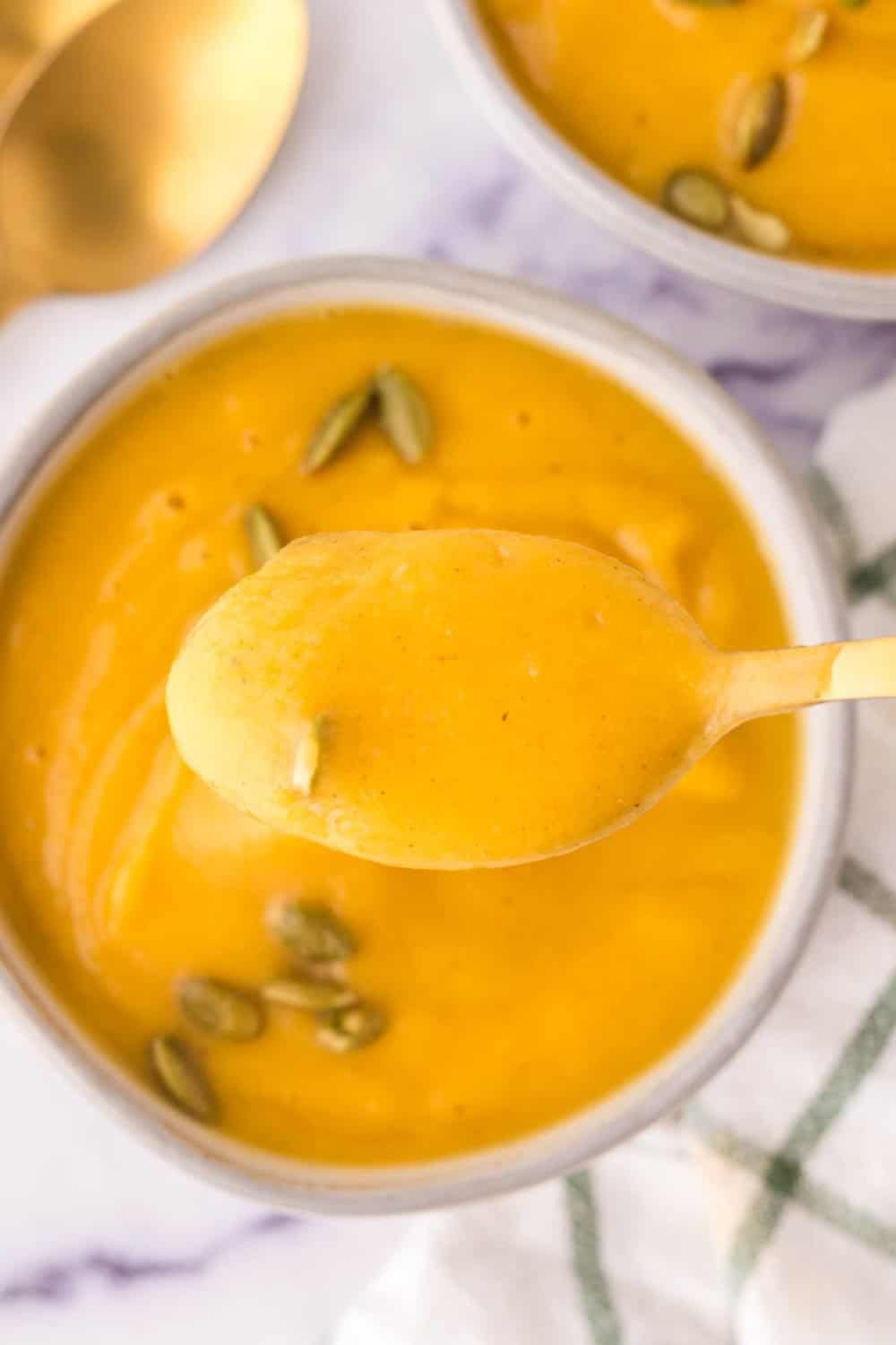 white serving bowls of roasted butternut squash soup with pumpkin seeds on top