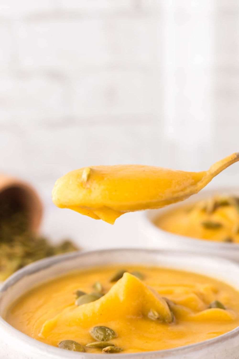 side view of a POV spoonful of rich orange butternut squash soup