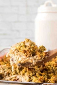 side view POV of a spoonful of chicken and stuffing over a casserole dish.