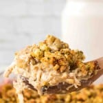 side view POV of a spoonful of chicken and stuffing over a casserole dish.