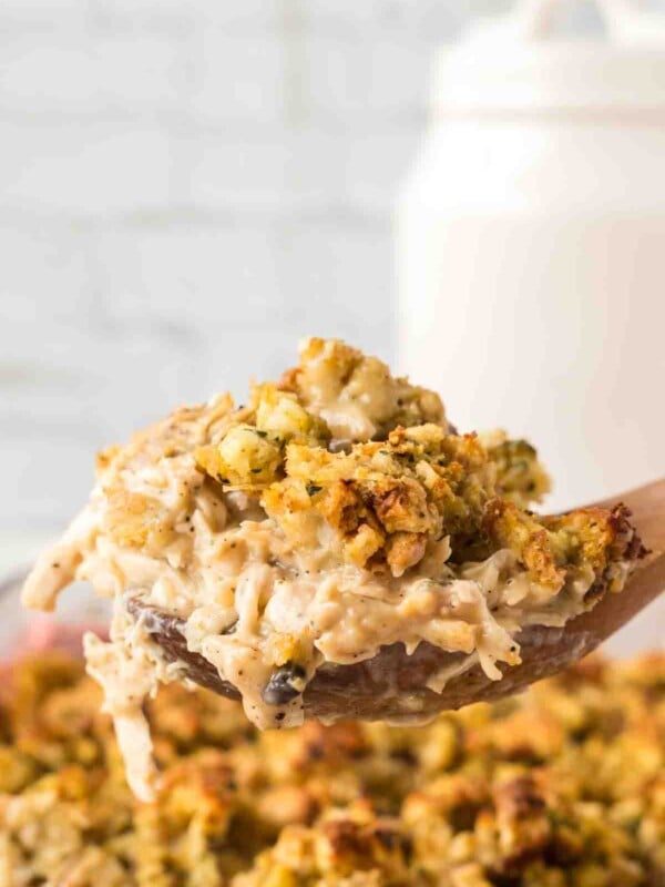 side view POV of a spoonful of chicken and stuffing over a casserole dish.