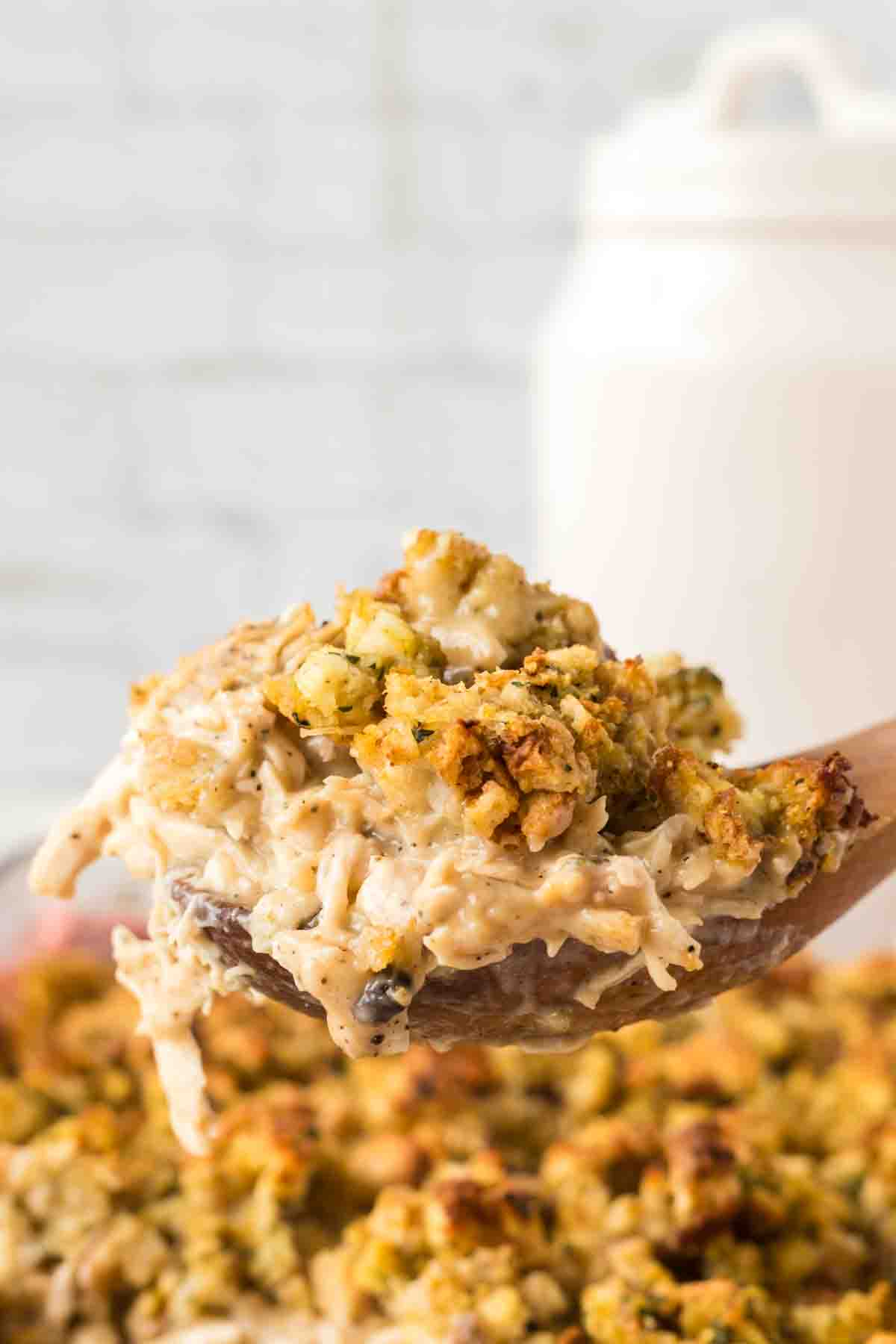 side view POV of a spoonful of chicken and stuffing over a casserole dish