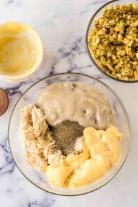 mixing ingredients in a clear bowl for chicken and stuffing casserole.
