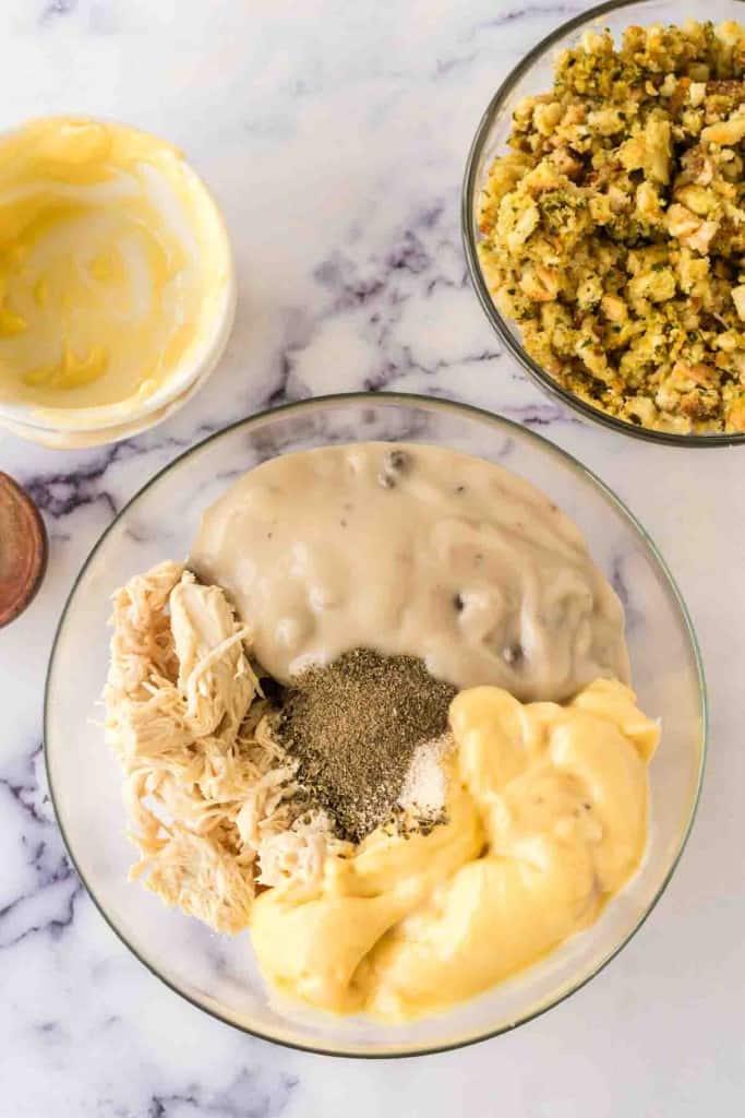 Mixing ingredients in a clear bowl for chicken and stuffing casserole. 
