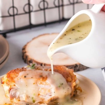 chicken gravy poured over baked chicken served on a round plate