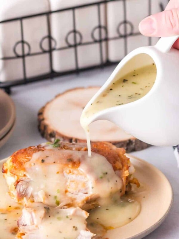 chicken gravy poured over baked chicken served on a round plate