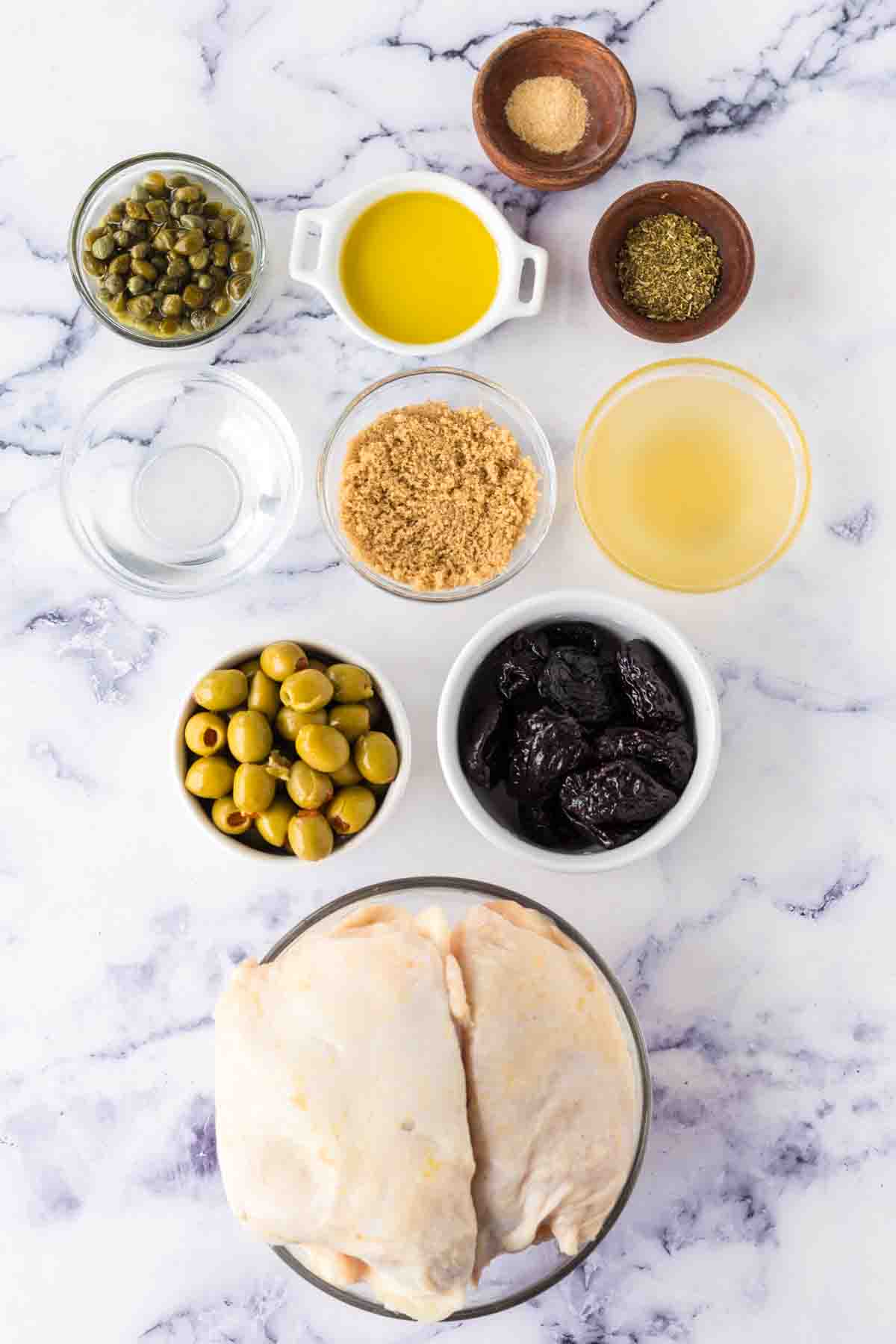 top view of portion dishes of raw ingredients over chicken marbella