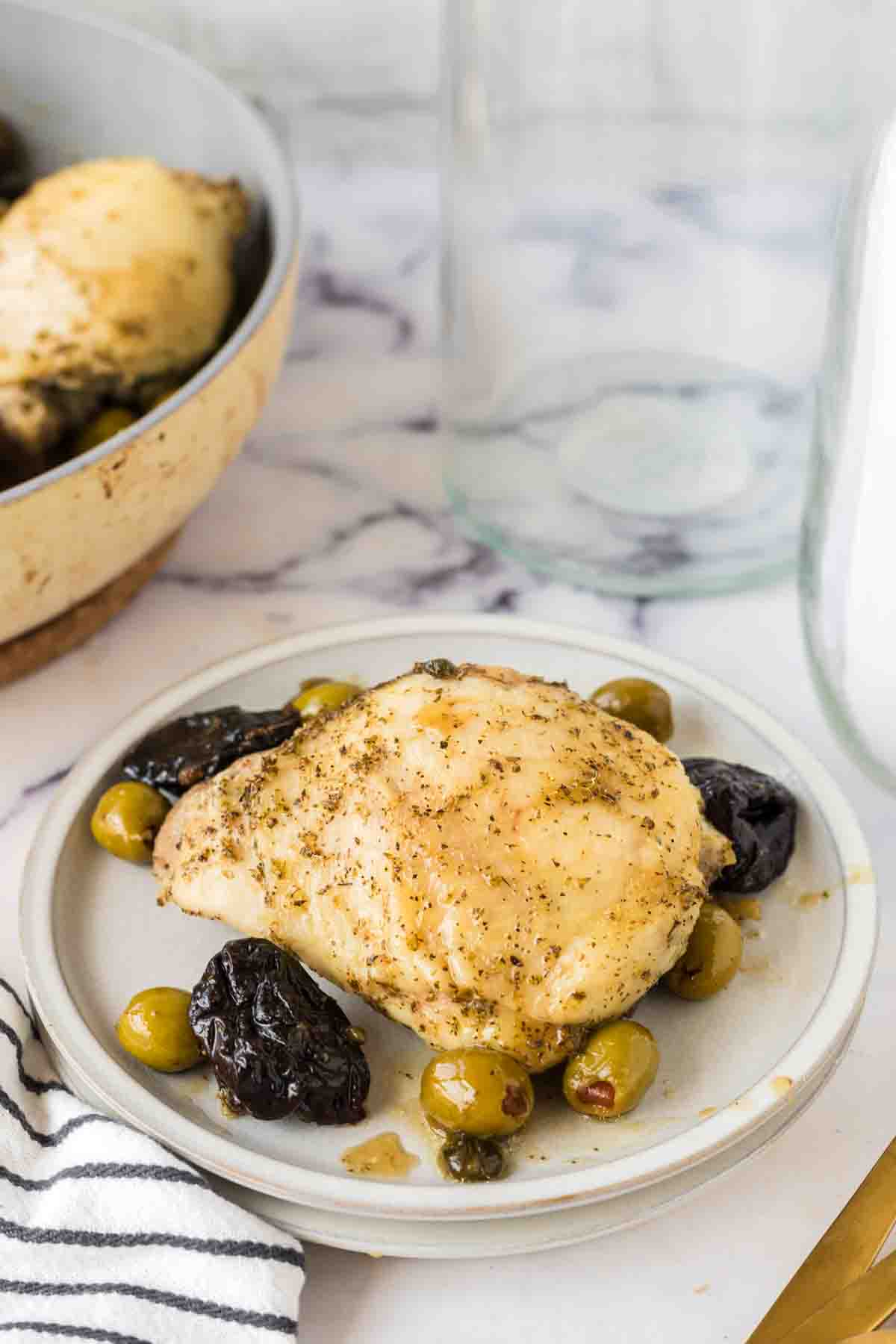 top view of a round white plate with chicken marbella recipe with dates and olives around