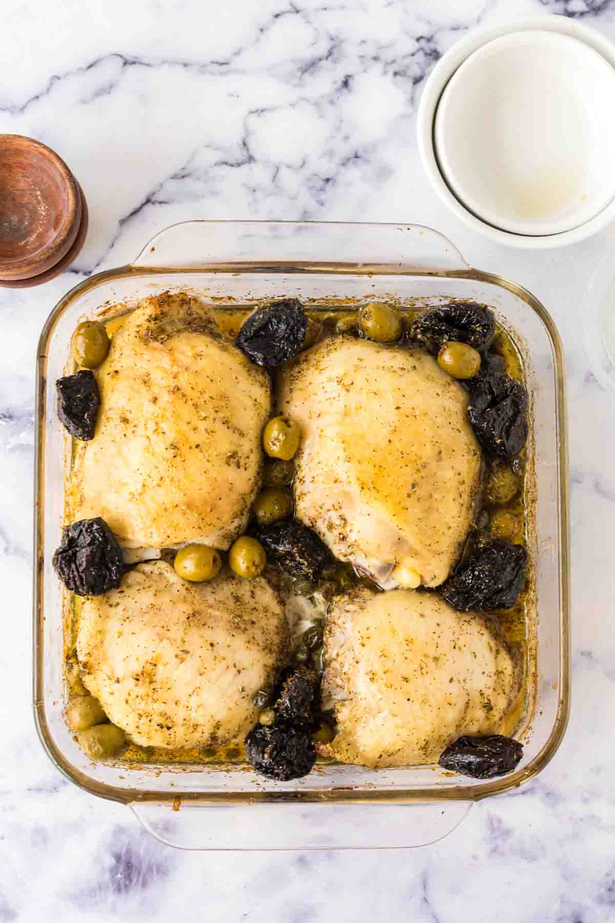 four breasts in a square casserole dish with chicken Marbella recipe inside