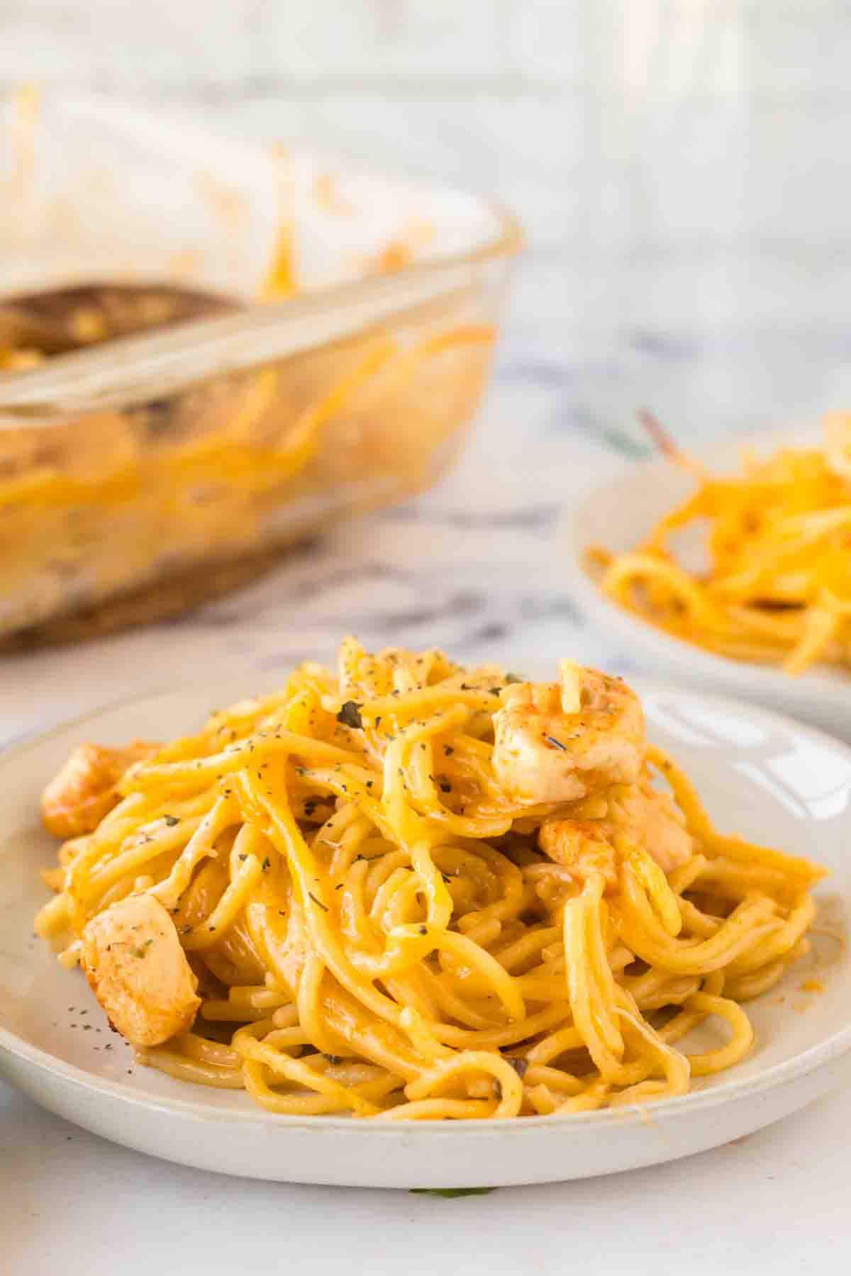 side view of a round white plate with chicken spaghetti on it