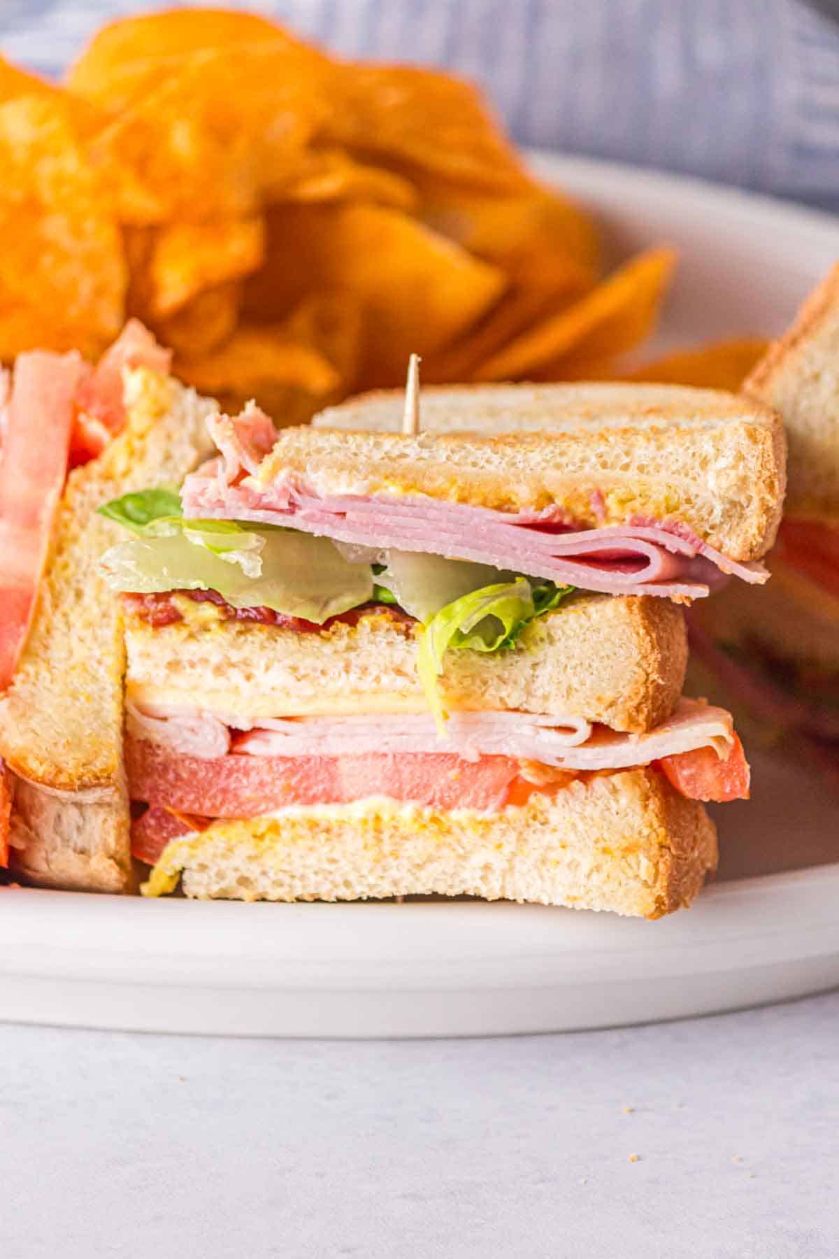 Close up view of a club sandwich served with chips. 