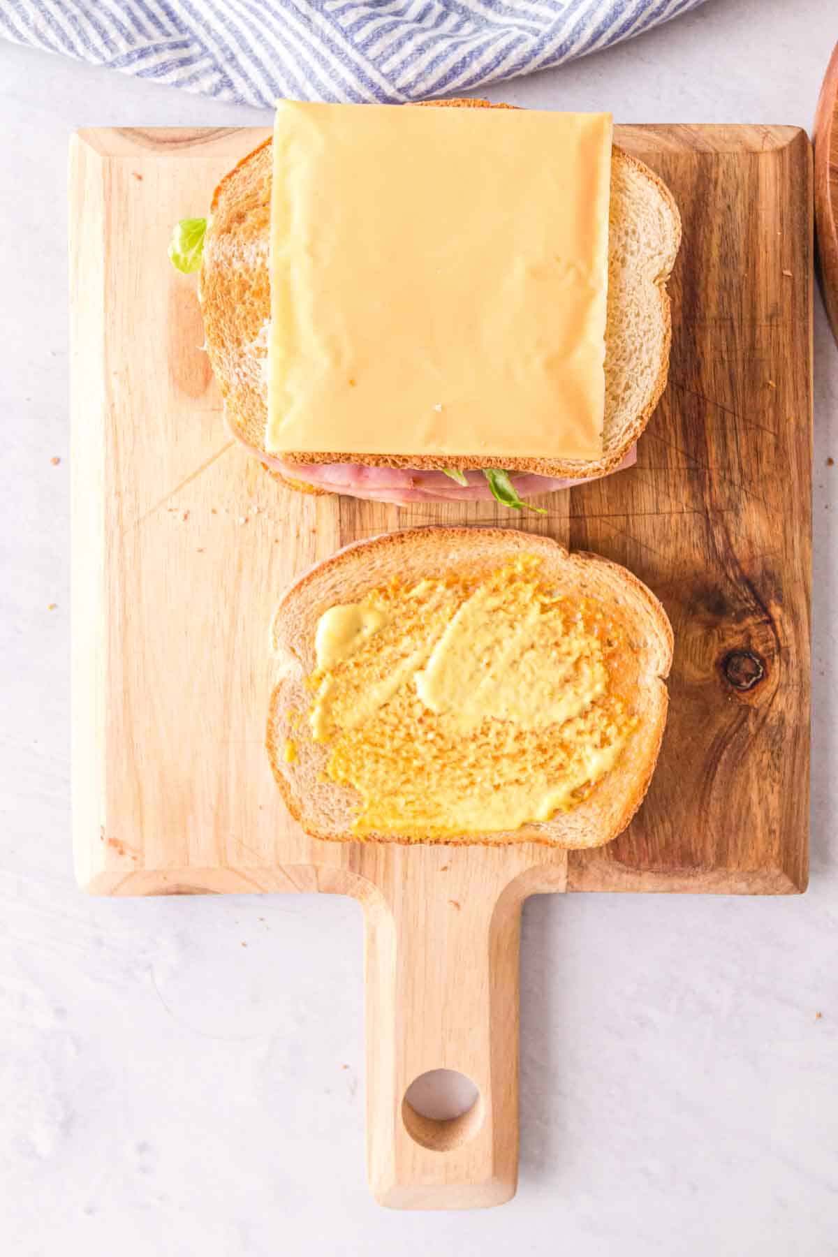 Adding the top layer of bread to the club sandwich.