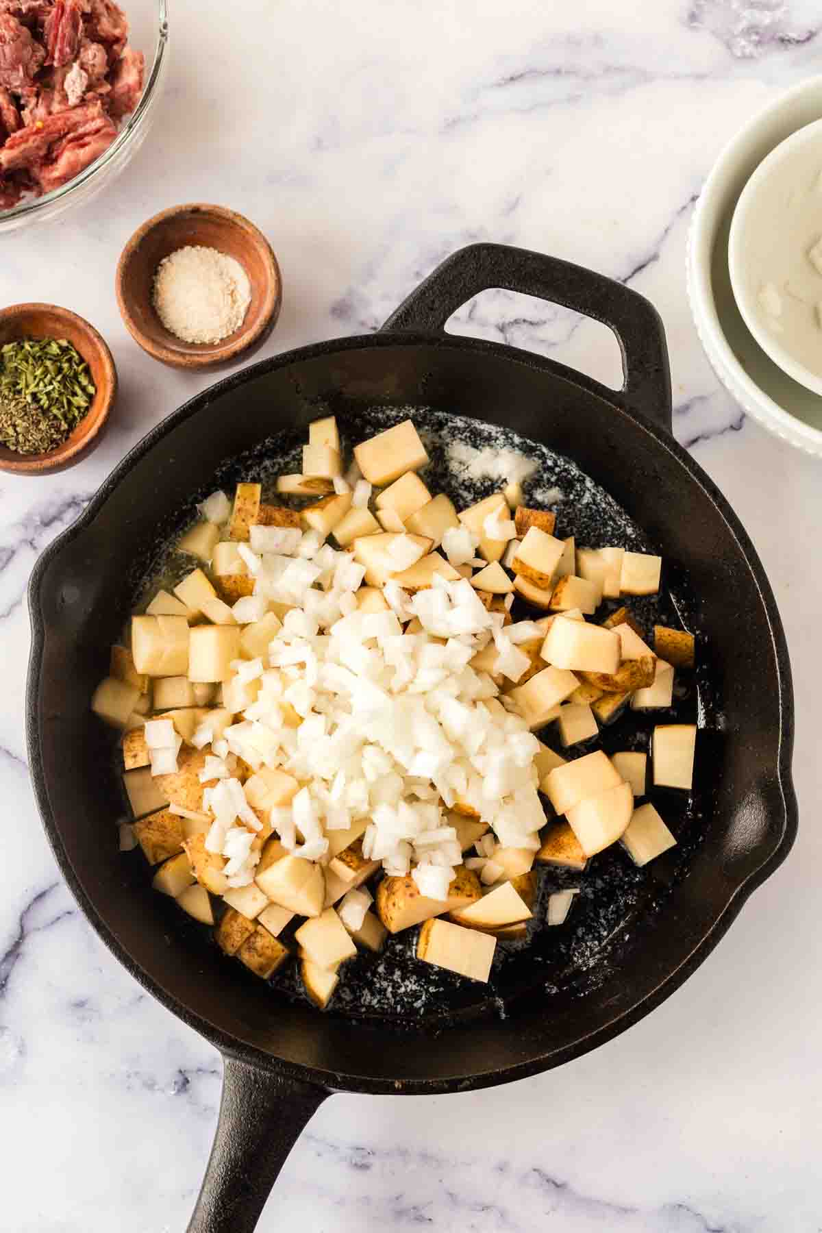 Diced potatoes and onions in a skillet.